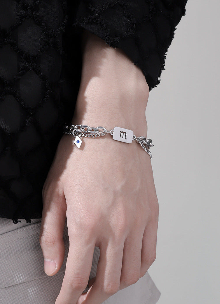 Silver astrology bracelet with a Scorpio charm and delicate chain details, worn on the wrist with a fashionable black ensemble.