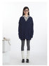 Full front view of navy cable knit set: V-neck sweater layered over striped shirt, coordinating shorts worn over grey tights.
