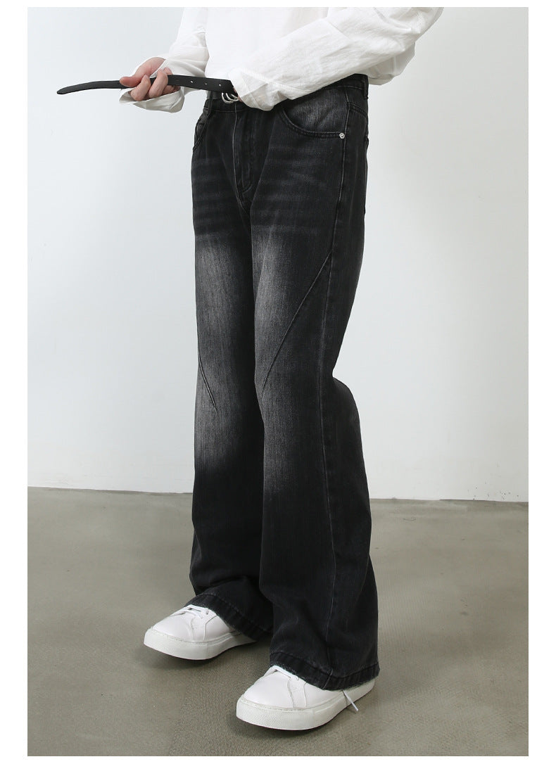 Close-up of model threading black leather belt through black wide-leg jeans with diagonal seam detail and white sneakers