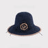 A navy woven sun hat with a beige crochet flower and trim, providing a stylish contrast and sun protection.