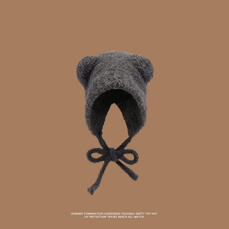 A heather gray teddy bear ear bonnet with black ties displayed against brown background, showing rounded ear design and fluffy texture