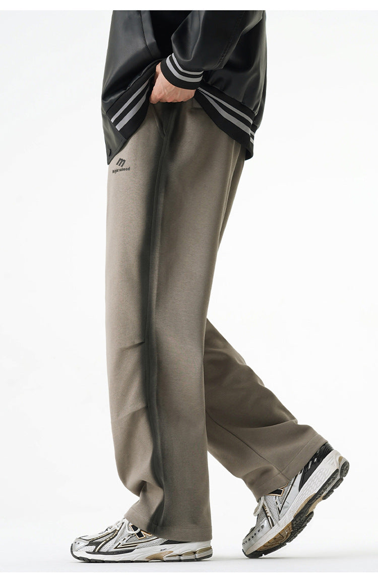 Gray wide-leg drawstring pants styled with a black varsity jacket and white sneakers