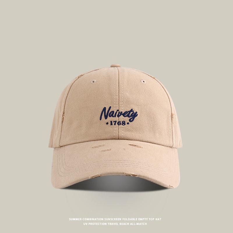Beige baseball cap with navy 'Naivety 1768' embroidered logo, front view