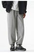 A model is wearing gray jogger sweatpants with a drawstring waistband and elastic cuffs