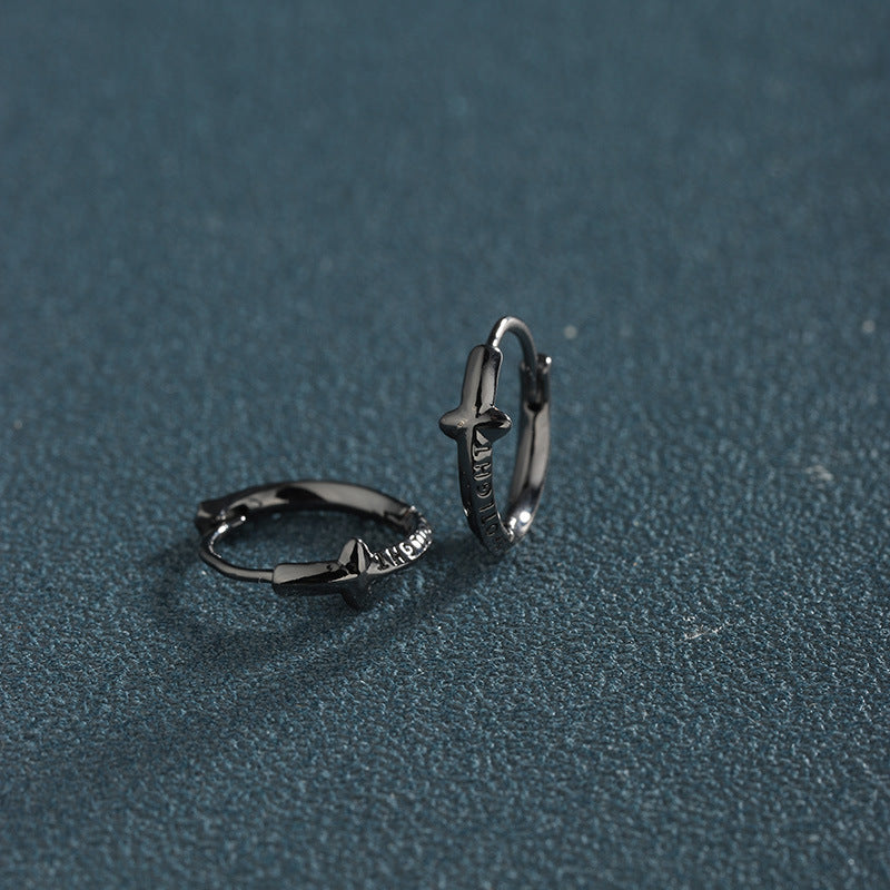Black color star hoop earrings on teal surface