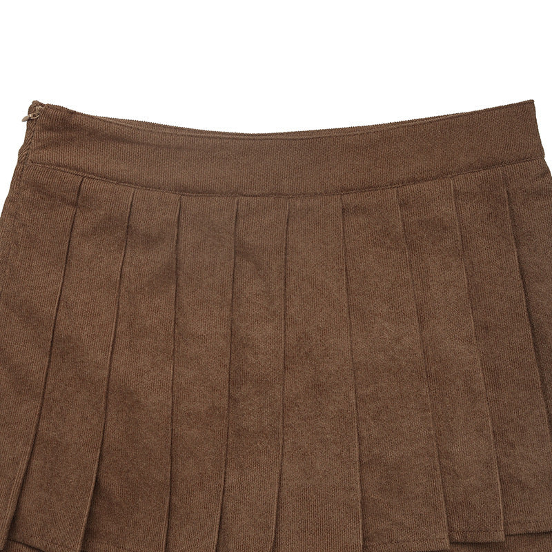 Close-up of the waistband and pleats of the brown mini skort, highlighting the fabric texture.