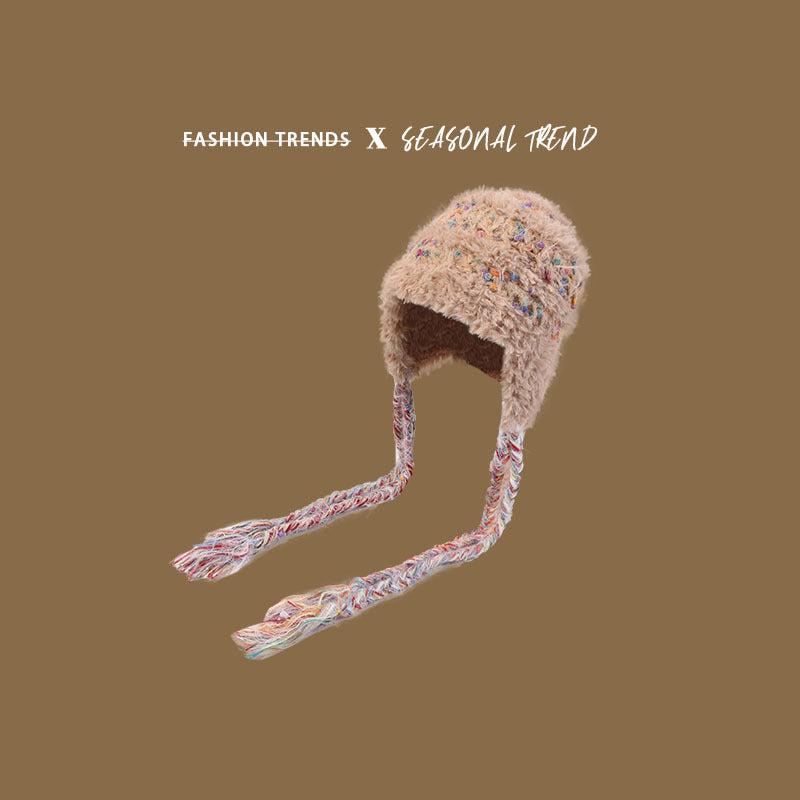 Beige fuzzy winter hat with multicolored speckles and braided earflaps, highlighting winter fashion details