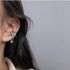 Silver ear cuff with rhinestones and heart charm worn with casual hairstyle