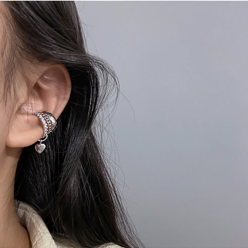 Silver ear cuff with rhinestones and heart charm worn with casual hairstyle