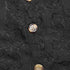 Close-up of tortoiseshell-style buttons on black lace fabric, emphasizing intricate details and craftsmanship.