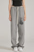 Close-up of grey sweatpants with elastic waistband, white drawstring and graffiti-style graphic print. Paired with black crop top
