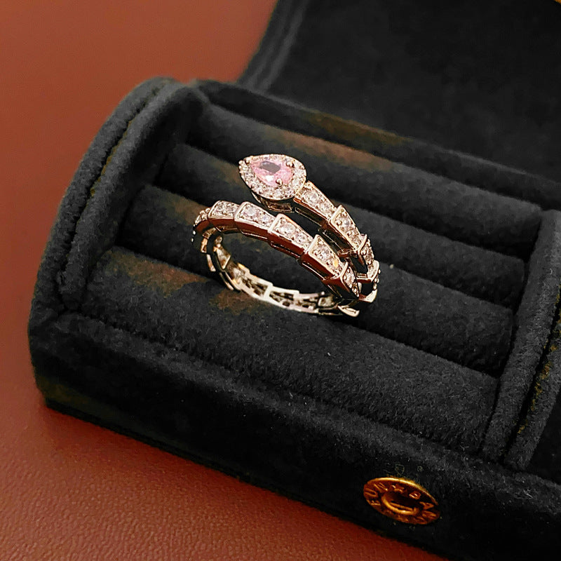 Serpent-style diamond ring with pink stone in elegant jewelry presentation box