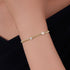 Gold heart charm bracelet worn on wrist, styled with a black top.