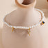Pearl charm bracelet draped around a ceramic vase, featuring lightning bolts and a blue gem.