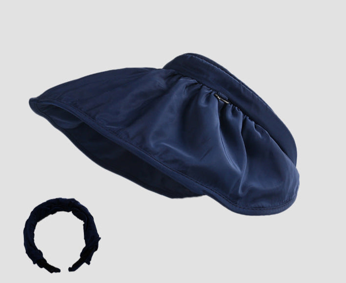  A dark navy blue sun visor hat with a detachable ruched headband, featuring a wide brim for UV protection.