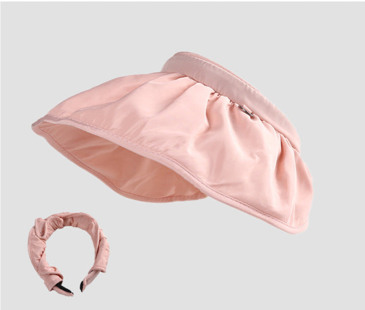 A soft pink sun visor hat with a ruched detachable headband, featuring a wide-brim design for sun protection.