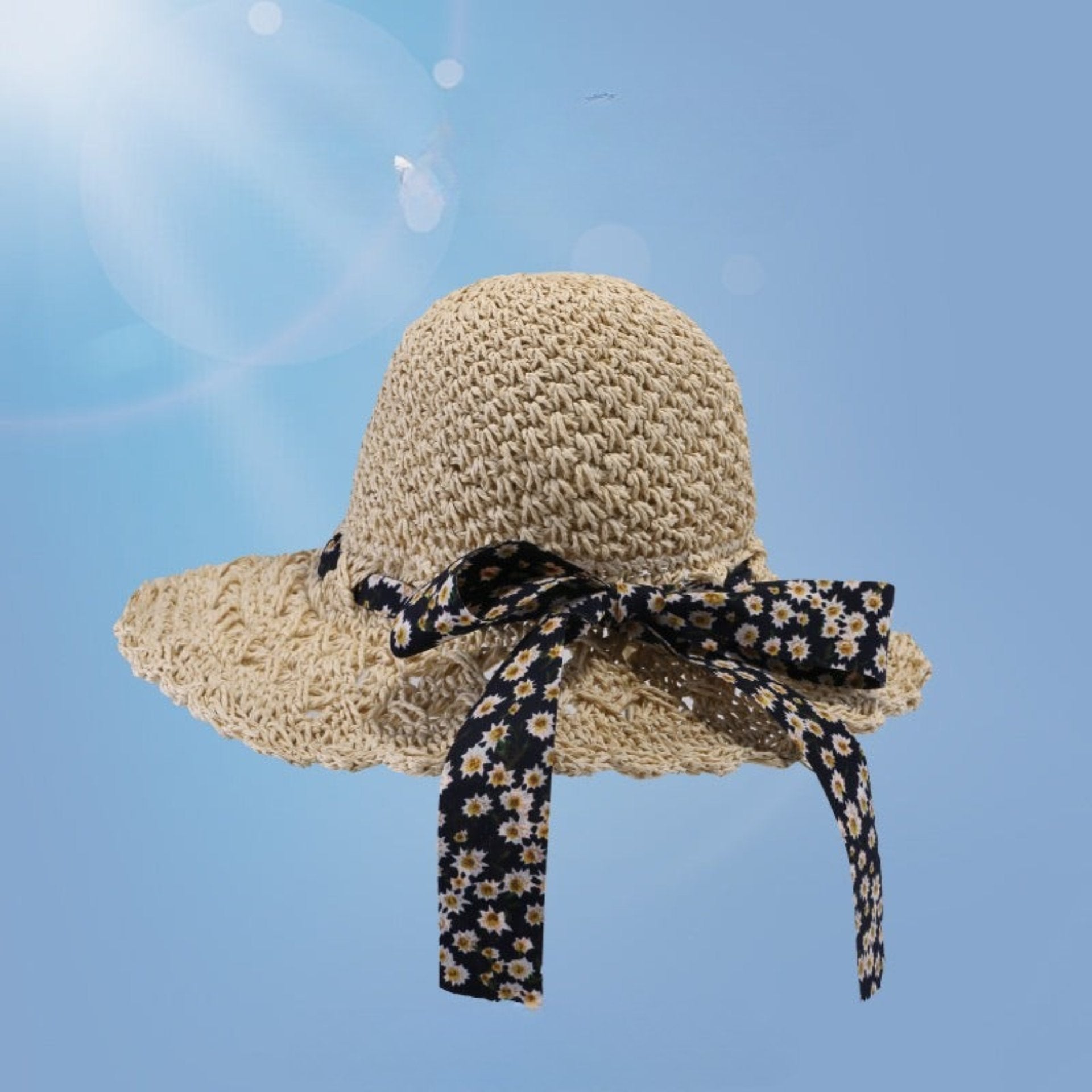 Beige woven straw sun hat with a navy floral bow, wide brim, and breathable open-weave pattern, placed on a blue gradient background.
