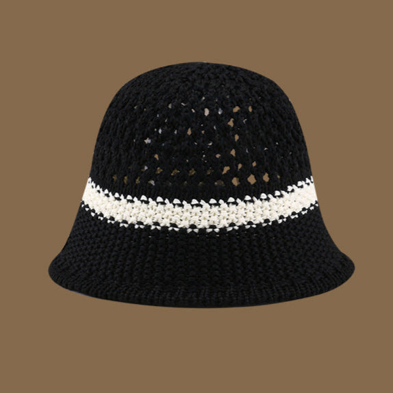 A black straw bucket hat featuring a contrasting white stripe and an open-weave top, offering a modern and elegant summer look.