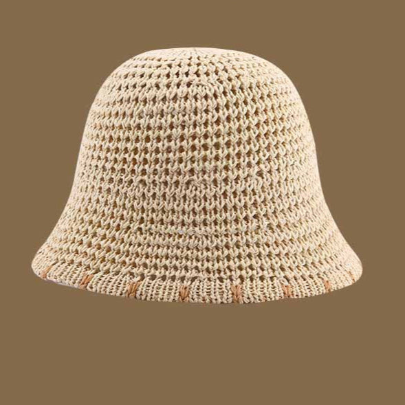 A beige straw bucket hat featuring an airy crochet design and subtle brown-trimmed brim, ideal for sunny days and travel.