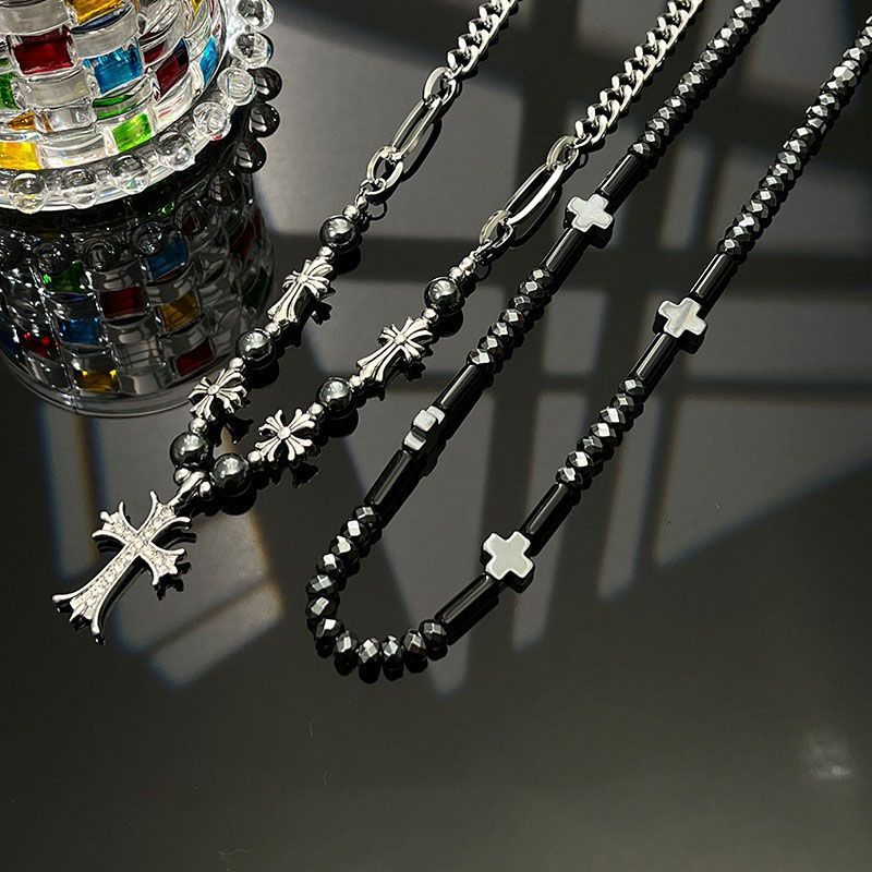 Black beaded cross necklaces with cross pendants on a dark surface