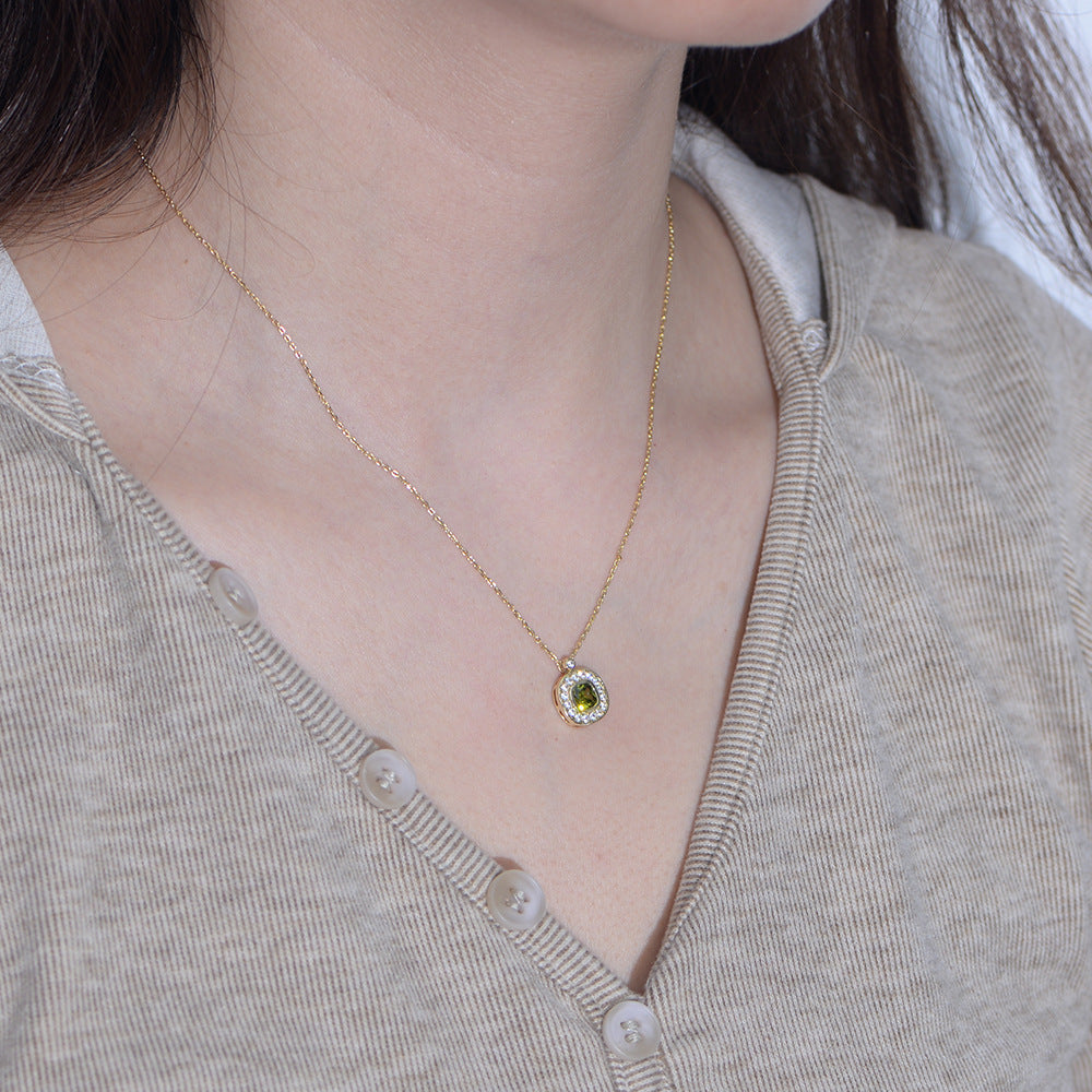 Side view of woman wearing gold green CZ pendant necklace, styled with casual outfit.