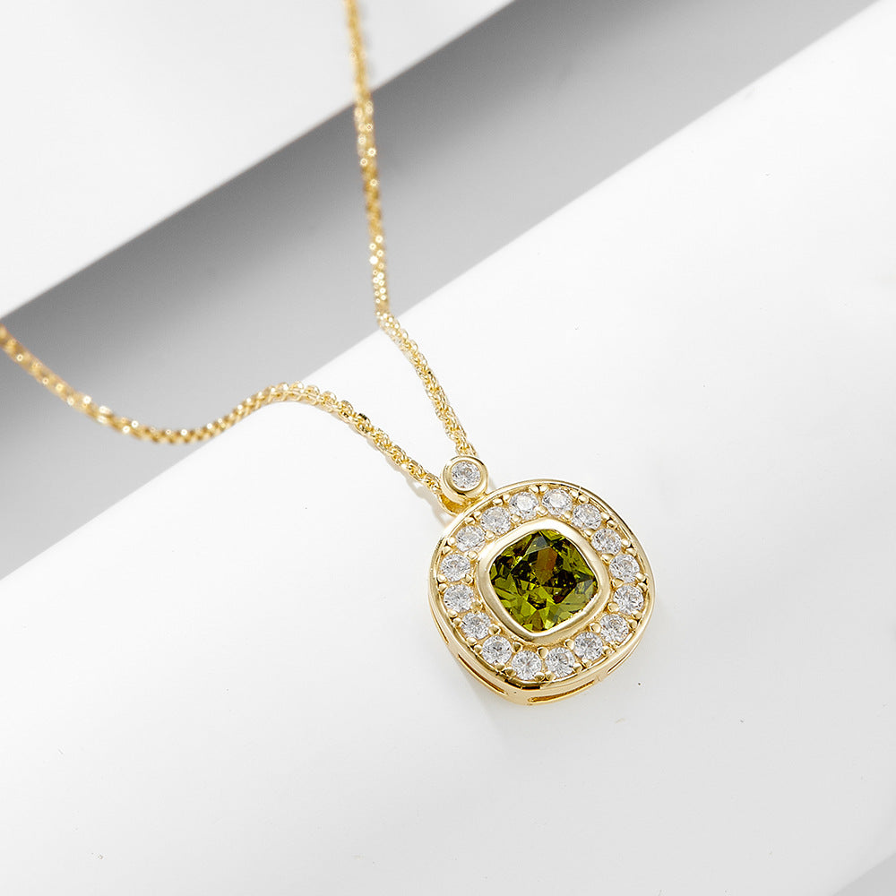 Close-up of gold necklace featuring green cushion-cut CZ stone and pavé halo.
