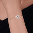 Woman wearing gold evil eye bracelet with central CZ eye charm.