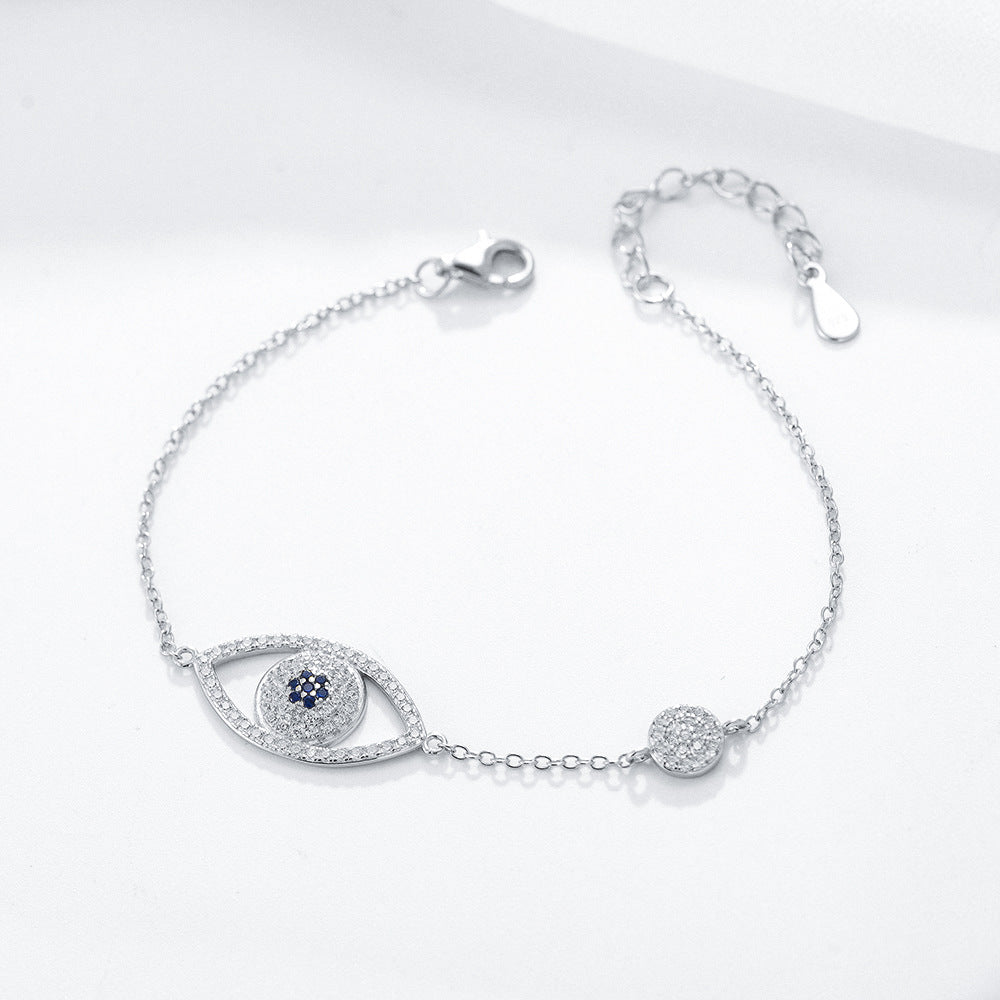 Silver evil eye bracelet with blue and clear CZ stones on white background.