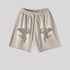 Beige cotton shorts with tonal cupid embroidery and elastic waistband, studio product shot