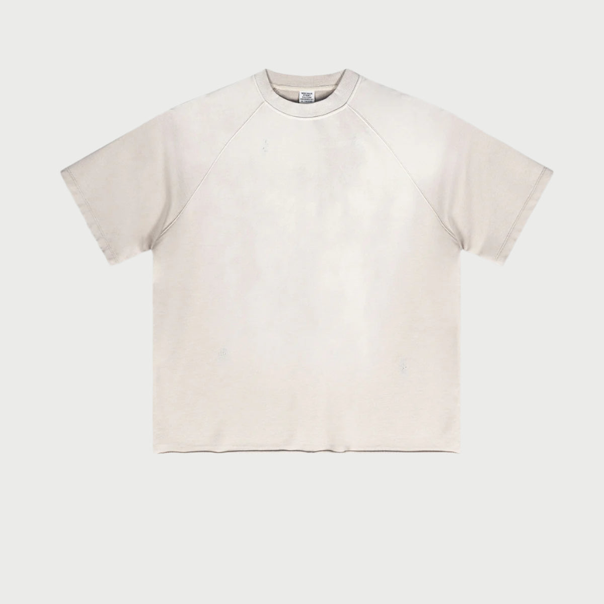 Cream colored oversized t-shirt with raglan sleeves displayed flat against light gray background