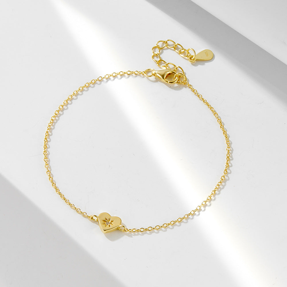 Gold heart charm bracelet with star-shaped CZ center on white background
