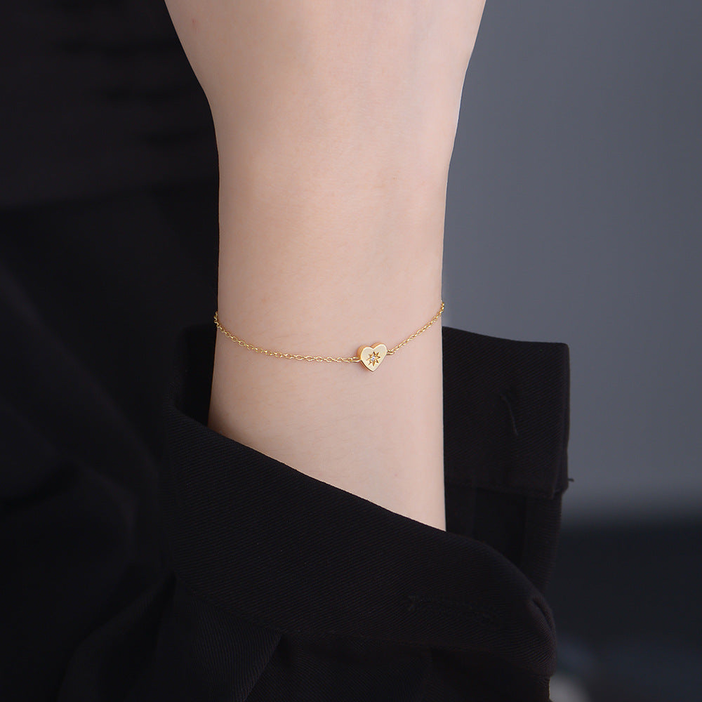 Model wearing dainty gold heart bracelet on wrist