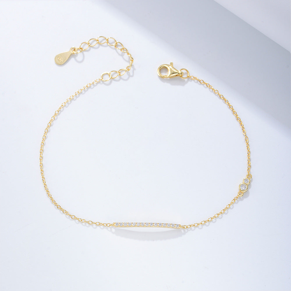 Gold bar bracelet with CZ accents laid flat on a white background.