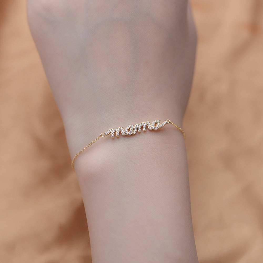 Gold MAMA charm bracelet worn on wrist.
