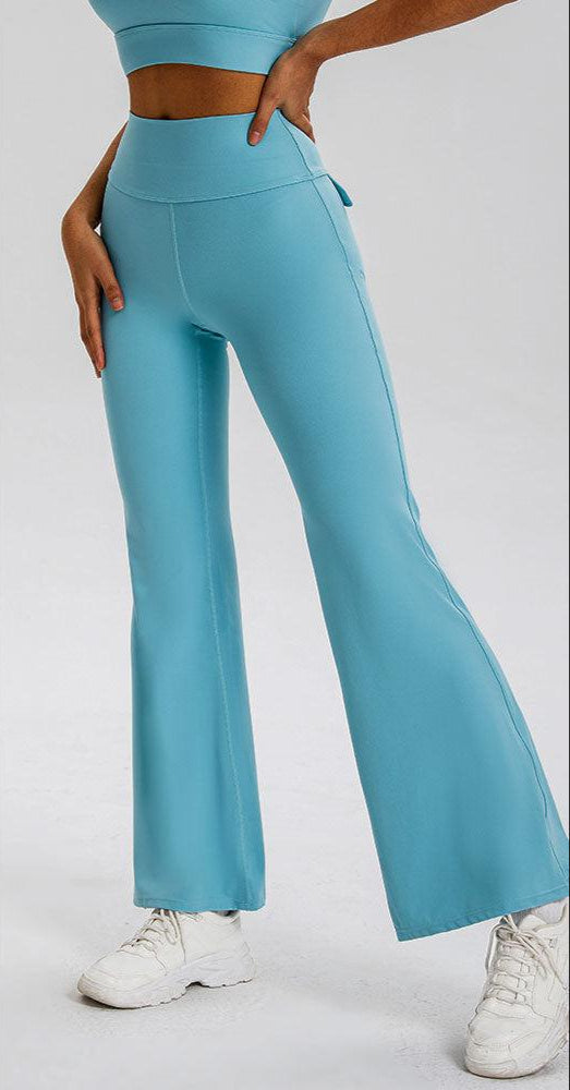 A close-up shot of a person wearing light blue flared yoga pants, showing high waistband detail and side seams, paired with a matching blue sports bra