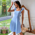 Light blue A-line dress with ruffle shoulder straps and square neckline, shown in sunlit room with decorative mirror