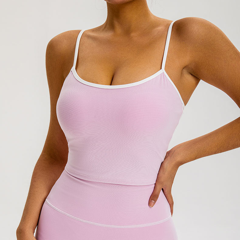 A woman is standing with hand on hip wearing a soft lavender athletic tank with white trim and matching high-waisted compression leggings