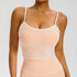 A woman is posing in a peach nude camisole top with white trim and matching high-waisted leggings showing seamless compression fit