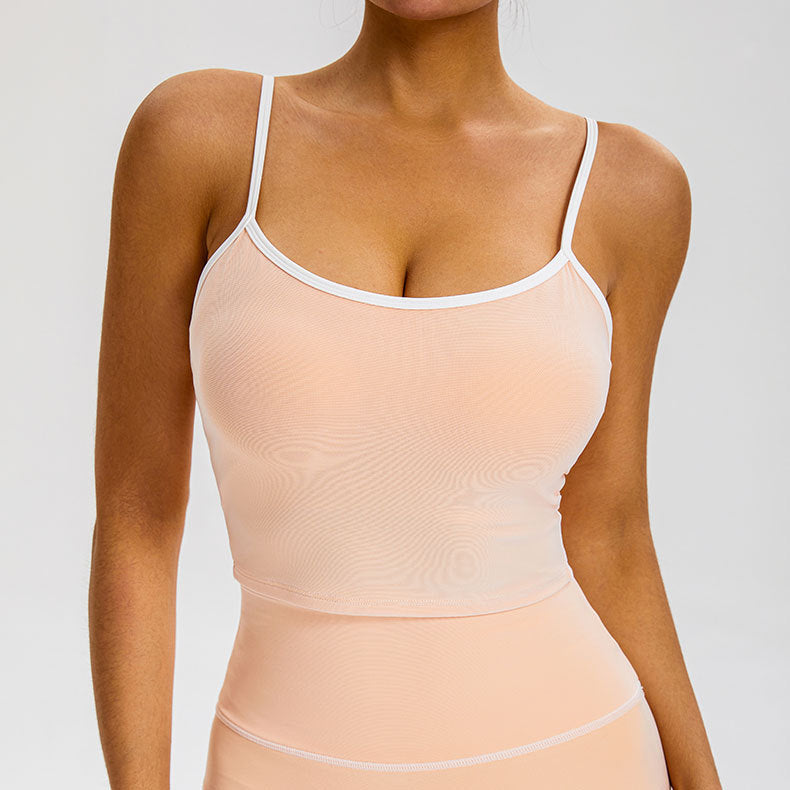 A woman is posing in a peach nude camisole top with white trim and matching high-waisted leggings showing seamless compression fit