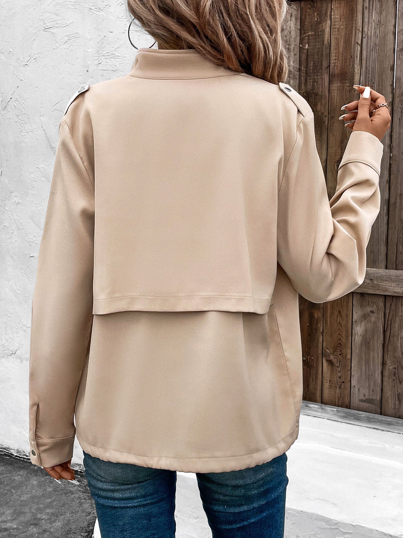 Women's beige utility jacket with front pockets and button details, styled casually with crop top