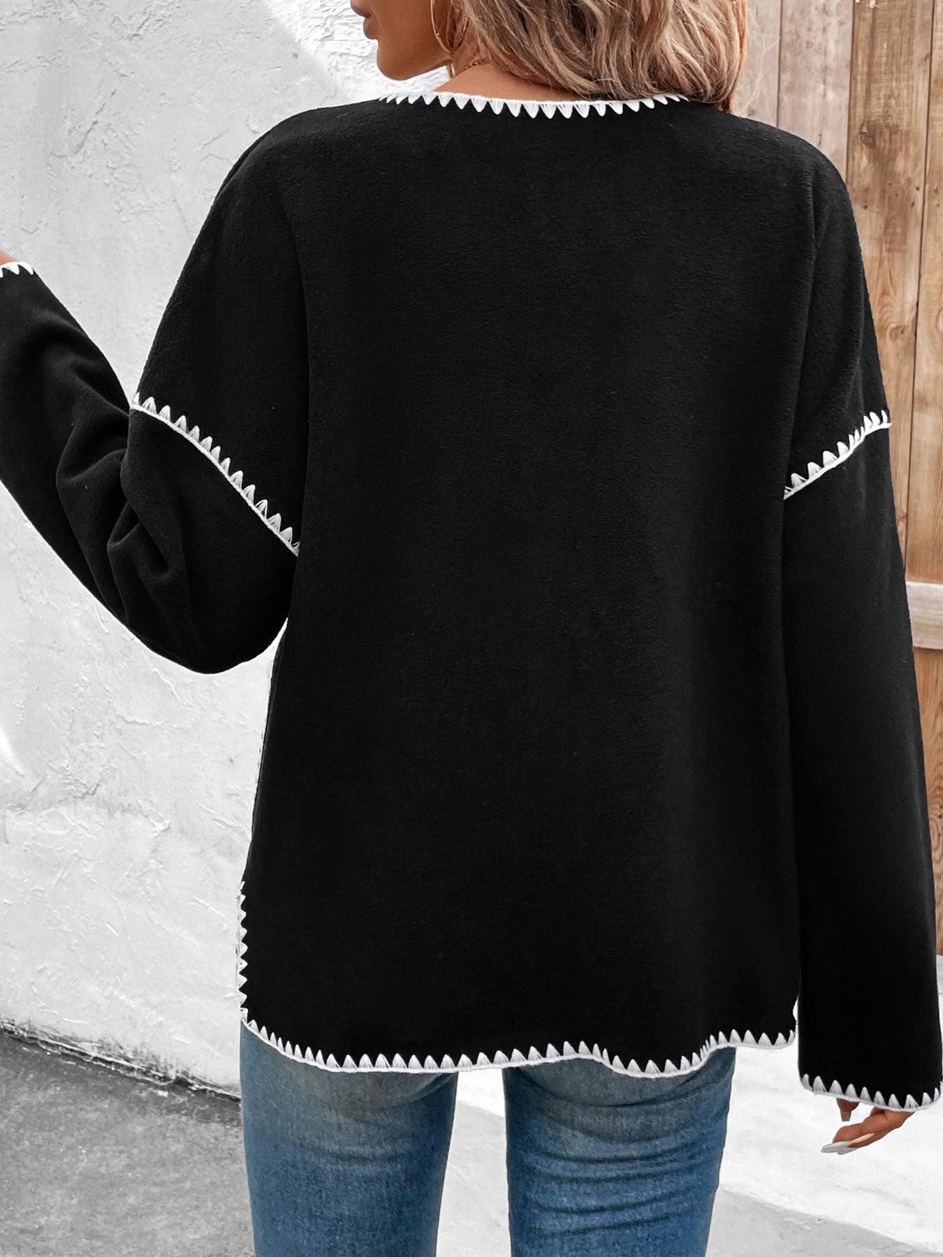 Women's black cardigan with white contrast stitching detail and front pockets