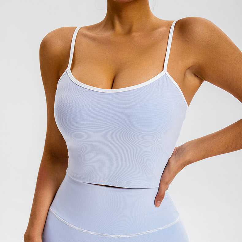 A woman is posing with hand on waist wearing a pale blue seamless camisole with white trim detail and matching high-waisted bottoms