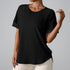 Black workout top featuring rolled cuffs and curved hem, paired with light-colored bottoms