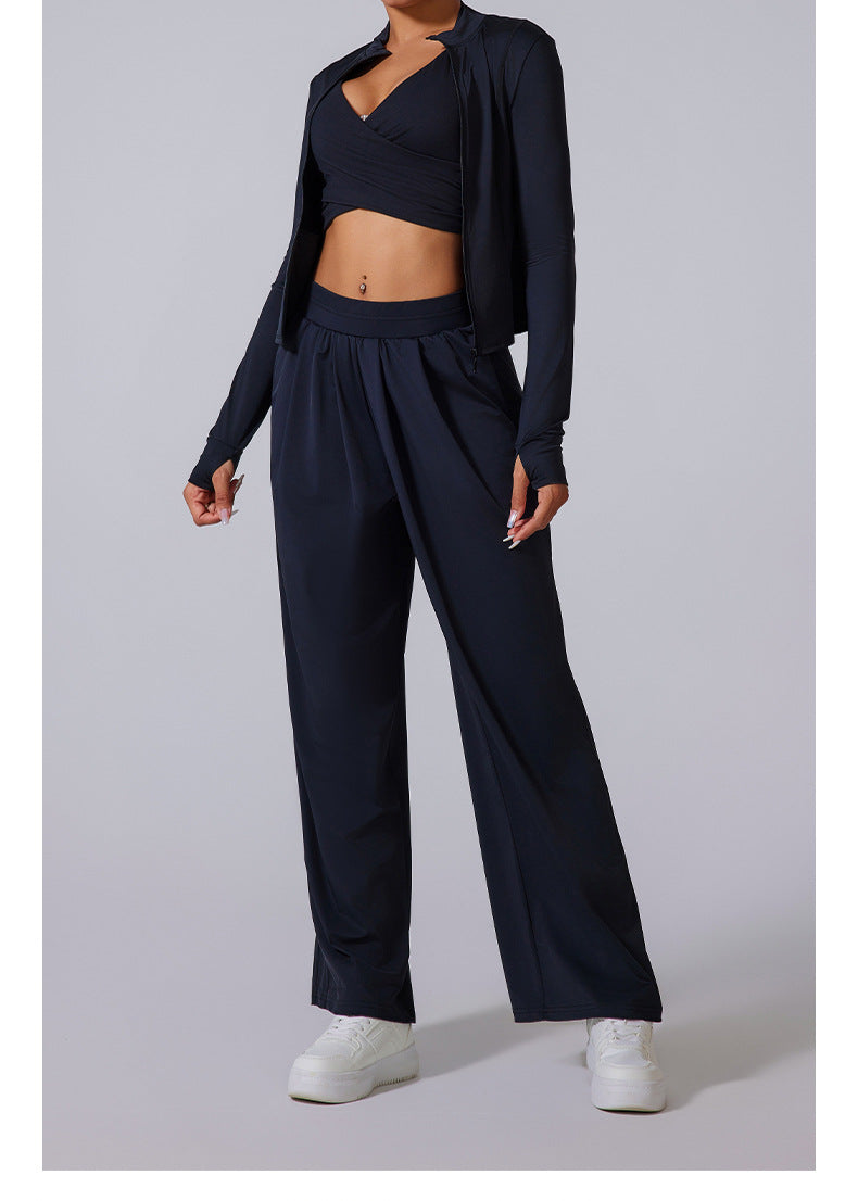 Model wearing black jacket, matching wide-leg pants and crop top with white platform sneakers.