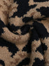 Macro texture shot of tan and black leopard print knit fabric showing stitch detail