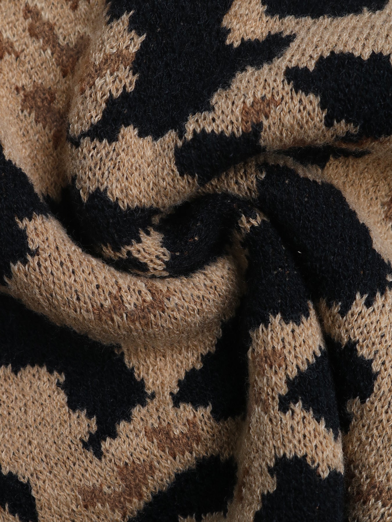 Macro texture shot of tan and black leopard print knit fabric showing stitch detail