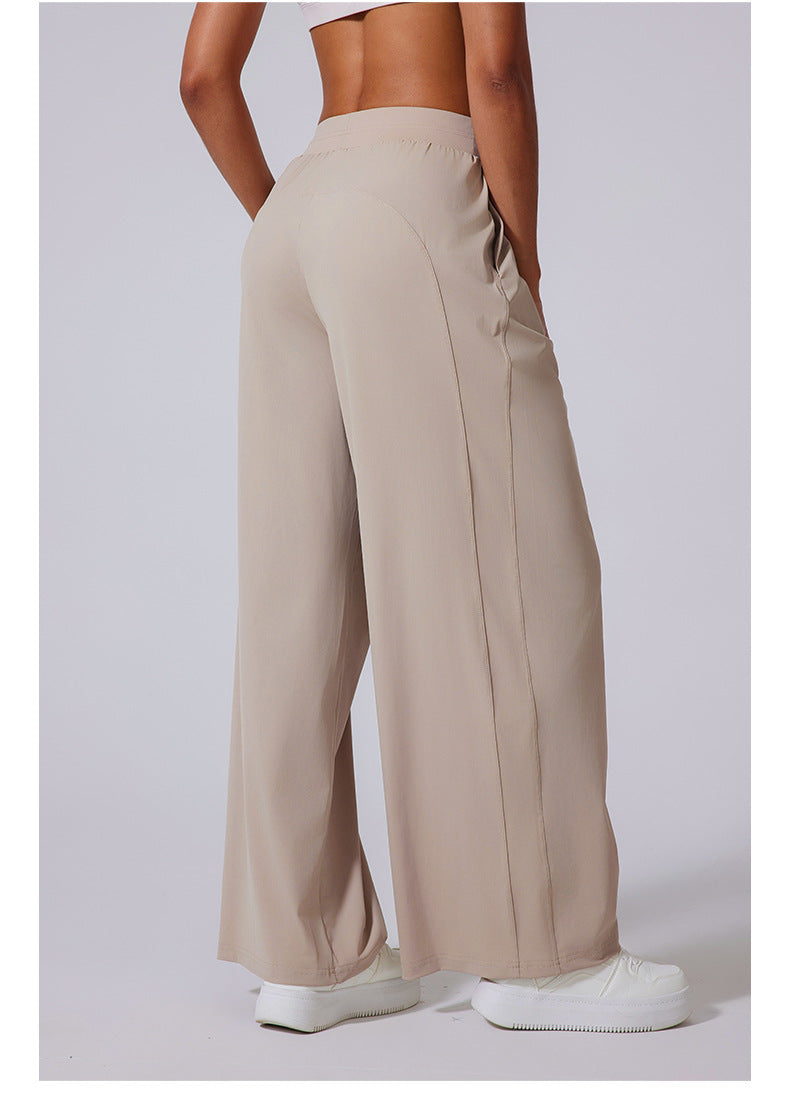 Side view of beige wide-leg lounge pants with high waist, paired with white sneakers.