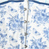 Close-up detail of a white and blue toile-print dress showing hook and eye closures with navy trim along the seam against white background