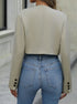 Women's cropped blazer in beige styled with high-waist jeans and layered necklaces