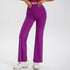 A person wearing bright purple flared yoga pants and matching sports bra, styled with white chunky sneakers against a white backdrop